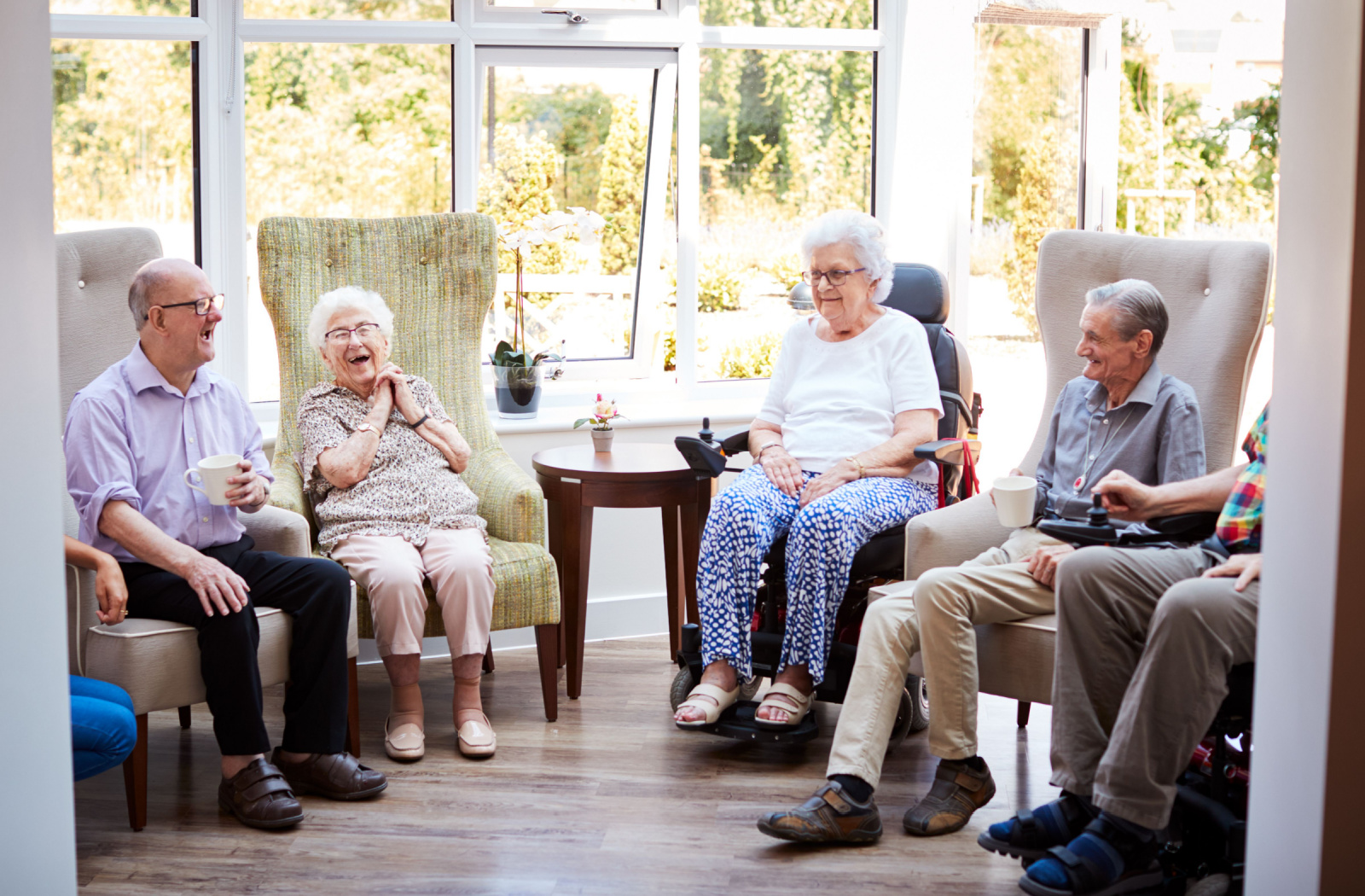 A group of seniors sitting down and talking to each other while enjoying a cup of tea in a senior living community