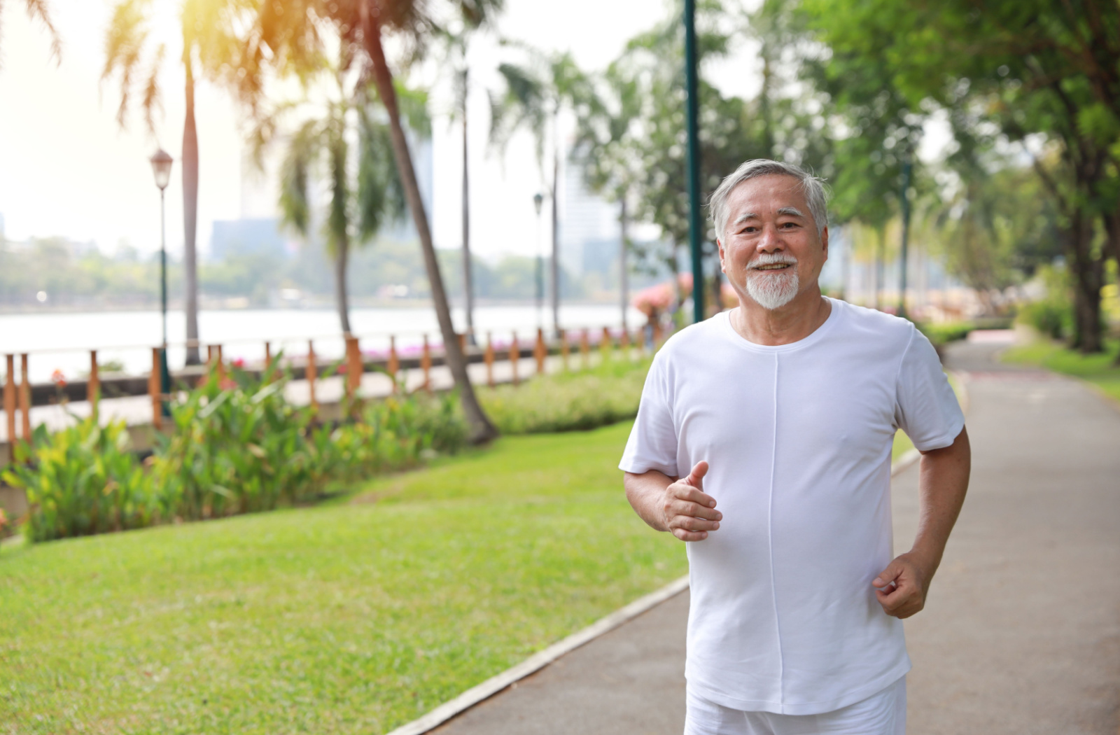 A senior man smiling looking directly at the camera while walking in a park